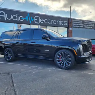 Black Cadillac SUV with tinted windows outside the Audio Electronics storefront
